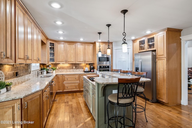 kitchen featuring a breakfast bar, a sink, a center island, stainless steel appliances, and light wood-type flooring