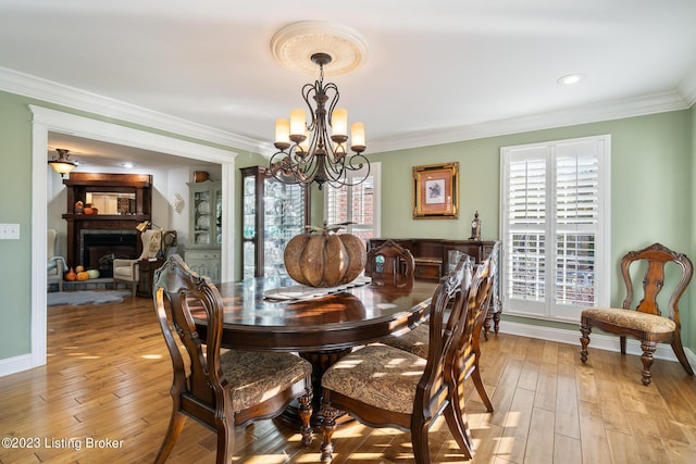 dining room featuring plenty of natural light, ornamental molding, a fireplace, and a chandelier