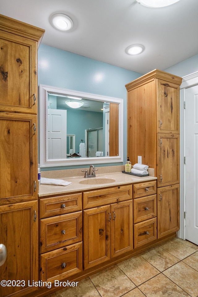 bathroom with an enclosed shower, vanity, and tile patterned flooring