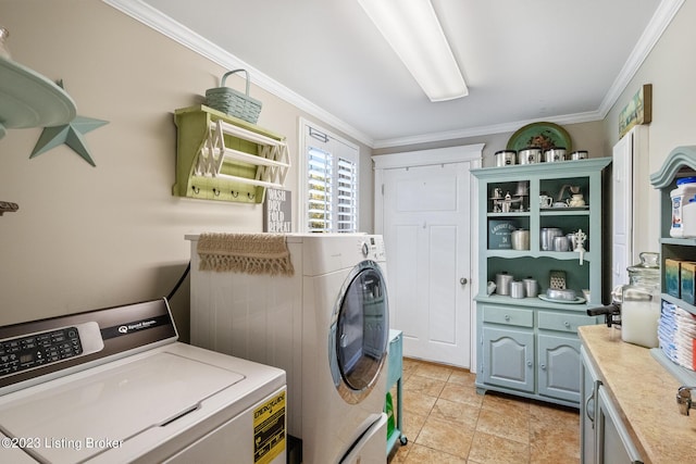 washroom featuring ornamental molding, cabinet space, and washer and dryer