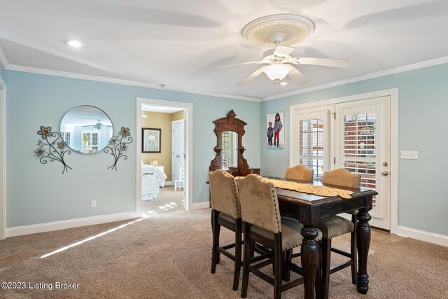 dining room with crown molding, a ceiling fan, baseboards, and light colored carpet