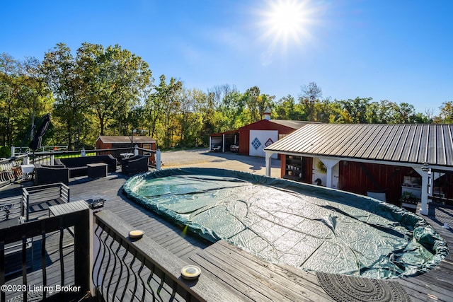 view of pool featuring a wooden deck, an outdoor structure, and outdoor lounge area
