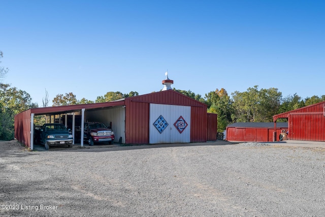 view of pole building with gravel driveway and a carport