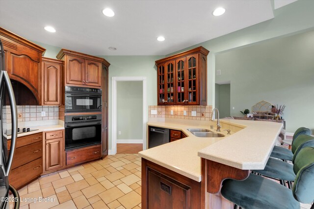 302 Hampton Rd, Brandenburg, KY 40108 - kitchen with a breakfast bar area, a sink, black appliances, a peninsula, and glass insert cabinets