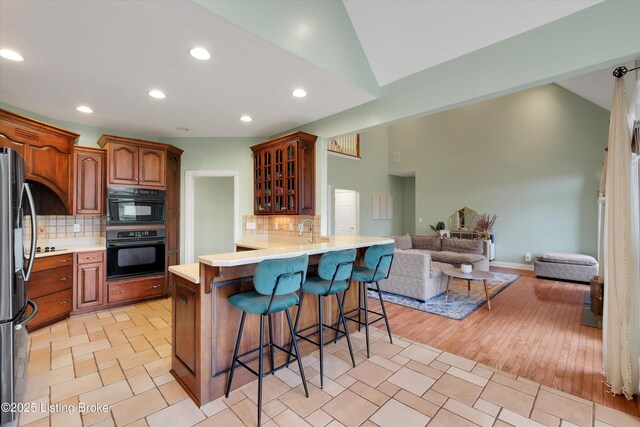 302 Hampton Rd, Brandenburg, KY 40108 - kitchen with freestanding refrigerator, open floor plan, a kitchen bar, backsplash, and glass insert cabinets