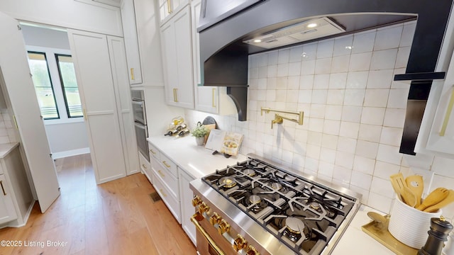 2045 W Rhudes Creek Rd, Elizabethtown, KY 42701 - kitchen with light countertops, backsplash, white cabinetry, and range