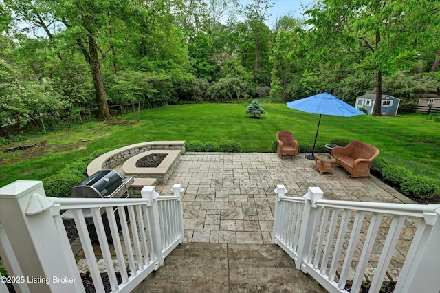 view of patio / terrace with a fire pit, an outbuilding, fence, and a shed