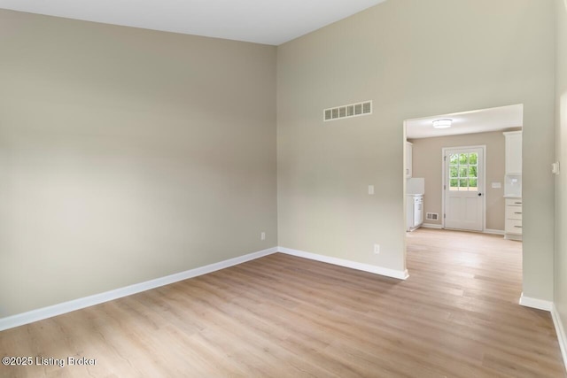 spare room featuring baseboards, light wood-style flooring, and visible vents