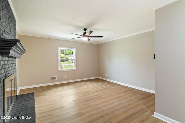 unfurnished living room with a brick fireplace, ceiling fan, visible vents, and crown molding