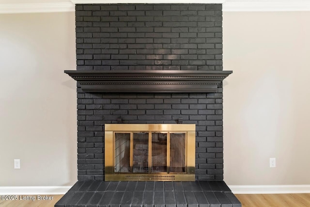 interior details featuring crown molding, baseboards, wood finished floors, and a fireplace