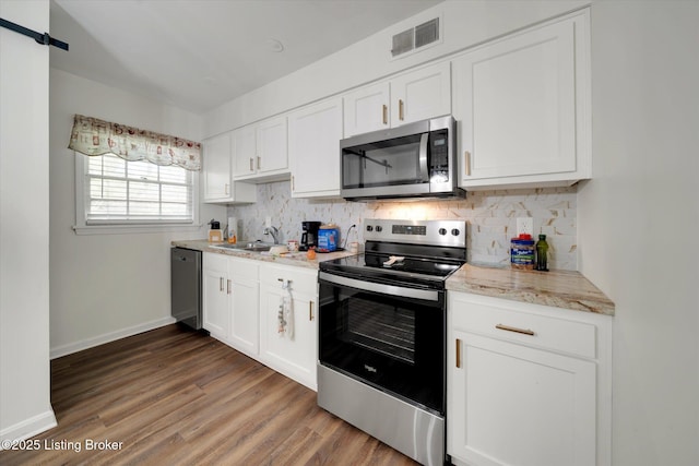 2100 Murray Ave, Louisville, KY 40205 - kitchen with appliances with stainless steel finishes, wood finished floors, tasteful backsplash, and white cabinets