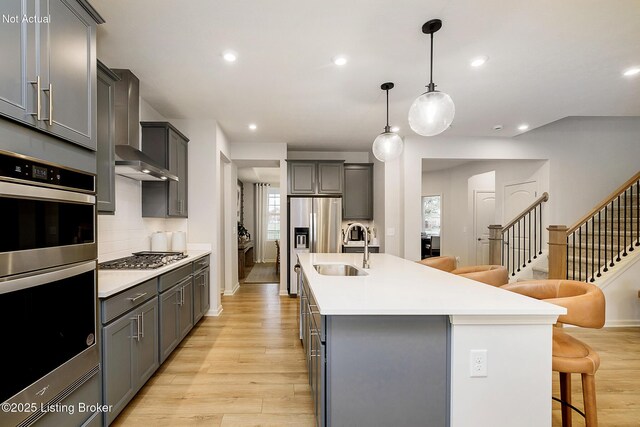 2309 Serenity Rdg Way, Louisville, KY 40023 - kitchen with a breakfast bar, wall chimney exhaust hood, a sink, gray cabinetry, and stainless steel appliances
