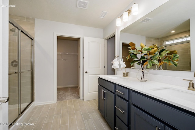full bathroom featuring a sink, a stall shower, and visible vents