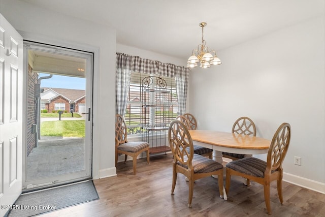 dining area with an inviting chandelier, baseboards, wood finished floors, and a healthy amount of sunlight