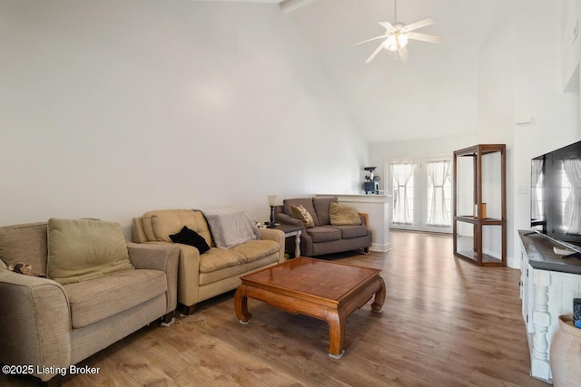living room with baseboards, high vaulted ceiling, ceiling fan, and wood finished floors