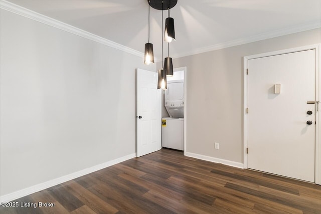 interior space with baseboards, ornamental molding, stacked washer and clothes dryer, and dark wood-type flooring
