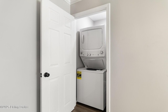 clothes washing area featuring stacked washer / dryer, laundry area, and dark wood-style floors