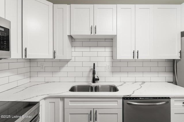 kitchen with light stone counters, a sink, white cabinetry, tasteful backsplash, and appliances with stainless steel finishes