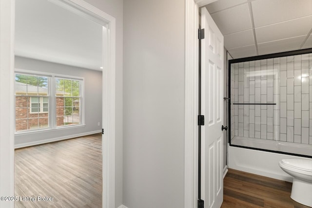 full bathroom featuring toilet, baseboards, enclosed tub / shower combo, and wood finished floors