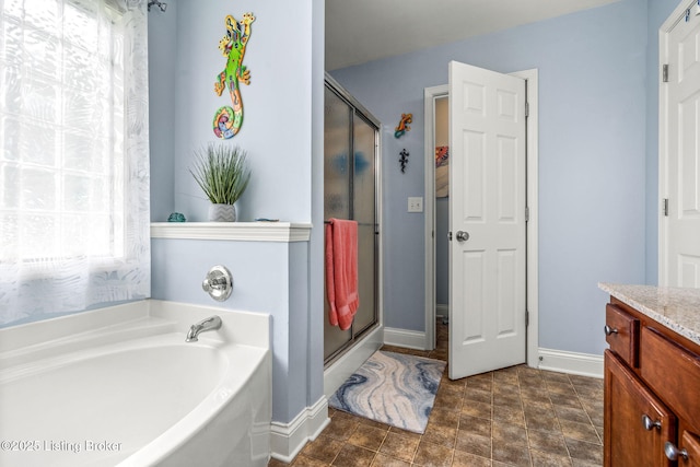 full bath with vanity, baseboards, a stall shower, and a bath