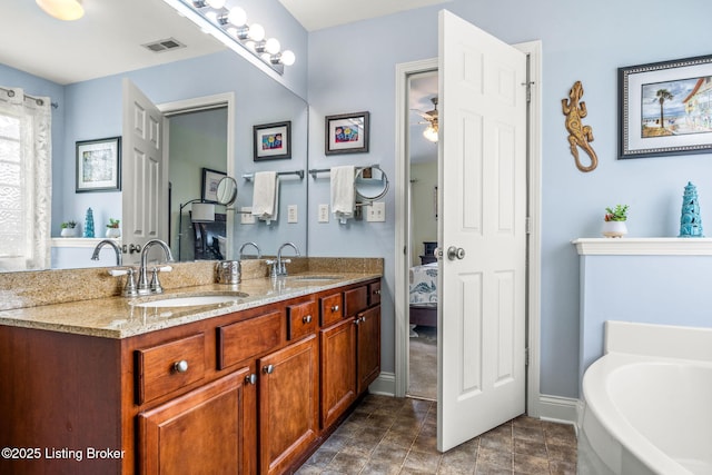 ensuite bathroom featuring double vanity, visible vents, a sink, and a garden tub