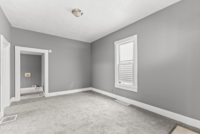 carpeted empty room with visible vents and baseboards