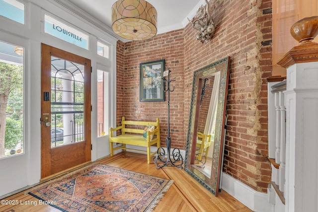 entrance foyer featuring light wood-type flooring, brick wall, and plenty of natural light