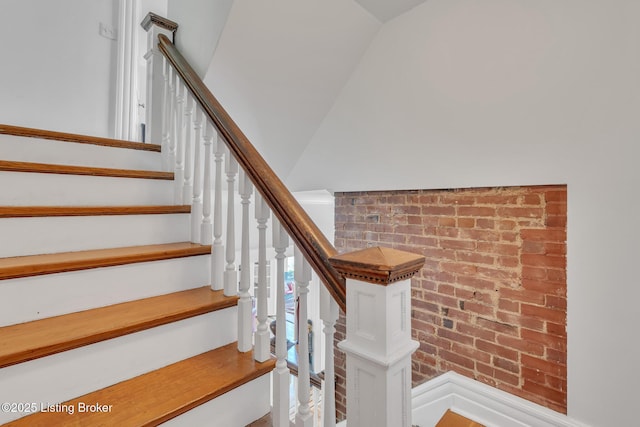 stairway featuring brick wall