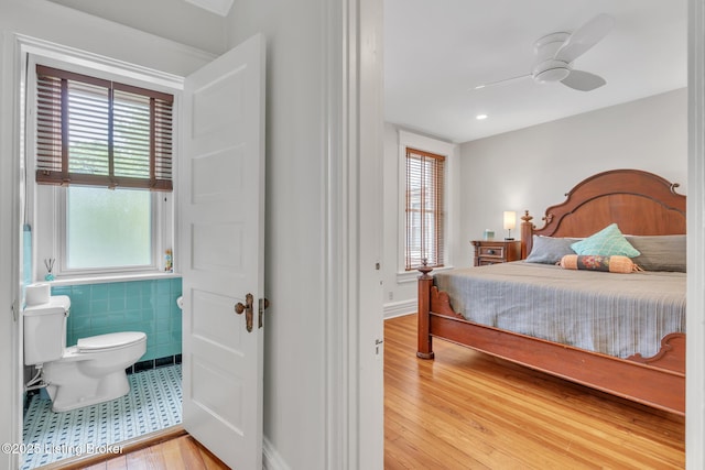 bedroom with light wood-style floors, tile walls, and ceiling fan