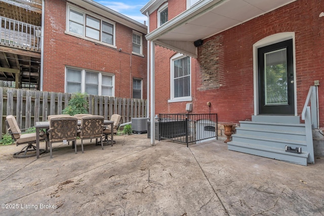 view of patio / terrace featuring entry steps, fence, cooling unit, and outdoor dining space