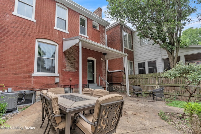 rear view of property featuring brick siding, fence, a patio area, central AC, and a chimney