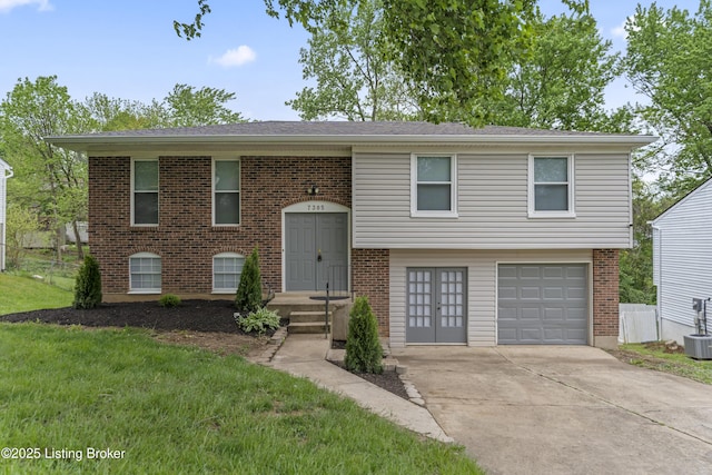 raised ranch featuring fence, an attached garage, brick siding, a front yard, and concrete driveway