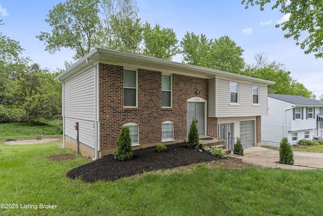 split foyer home with brick siding, a garage, a front yard, and concrete driveway
