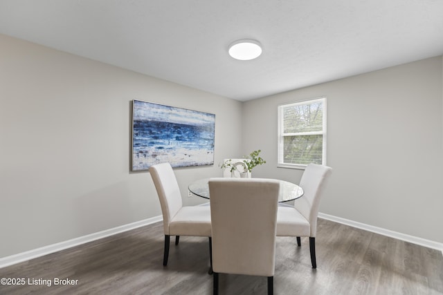 dining space with baseboards and wood finished floors