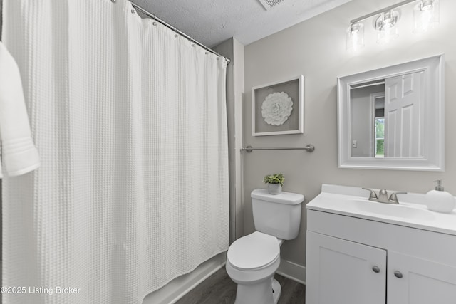 bathroom featuring vanity, toilet, a textured ceiling, baseboards, and wood finished floors