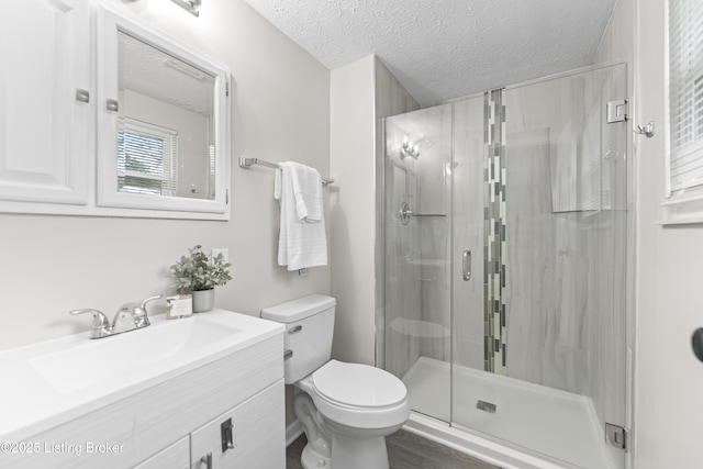 full bath featuring vanity, a stall shower, toilet, and a textured ceiling