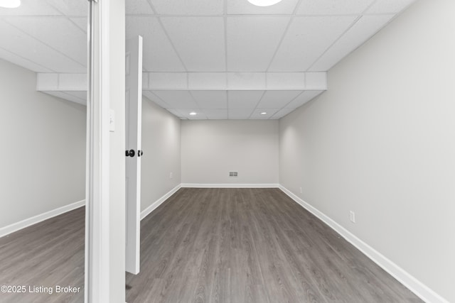 finished basement with baseboards, wood finished floors, and a paneled ceiling