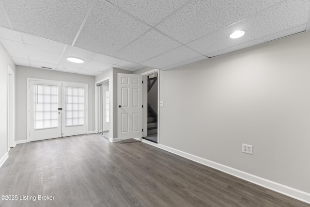 interior space featuring visible vents, stairs, baseboards, a drop ceiling, and dark wood-type flooring