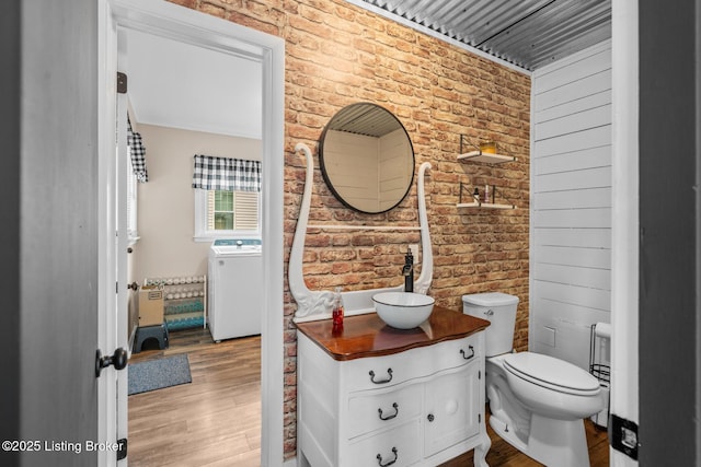 717 Highland Ave, Carrollton, KY 41008 - bathroom featuring vanity, washer / dryer, wood finished floors, brick wall, and toilet