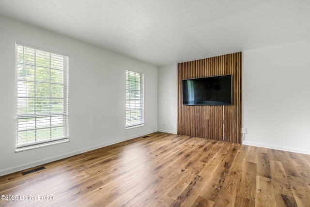 unfurnished living room with wood finished floors and baseboards