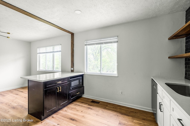 kitchen with open shelves, healthy amount of natural light, light countertops, and a textured ceiling