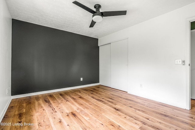 empty room featuring a ceiling fan, wood finished floors, and baseboards