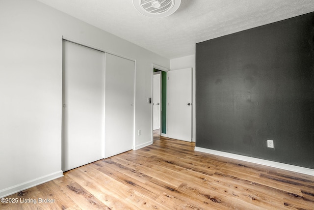 unfurnished bedroom with wood finished floors, baseboards, and a closet