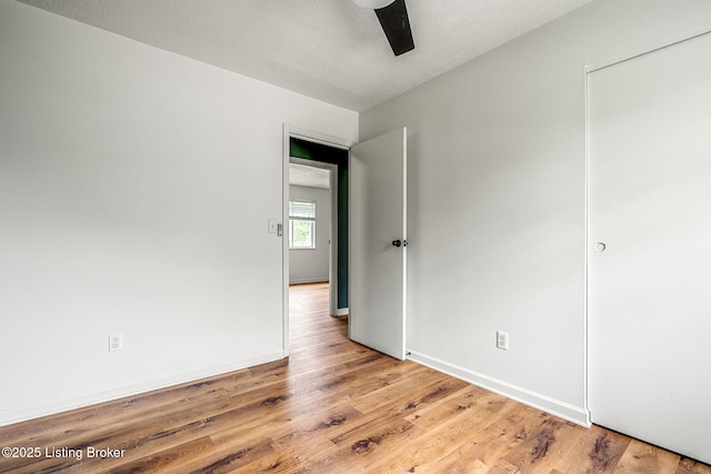 unfurnished room featuring light wood-style floors, ceiling fan, baseboards, and a textured ceiling