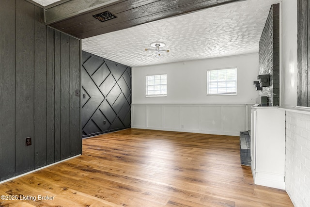 unfurnished room with a decorative wall, wood finished floors, and a textured ceiling