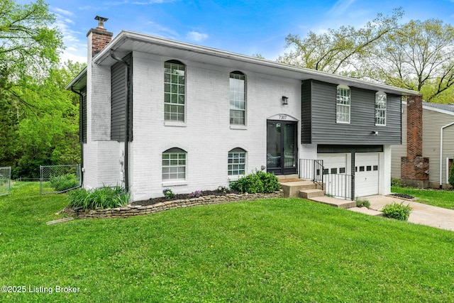 split foyer home featuring a chimney, concrete driveway, brick siding, and an attached garage