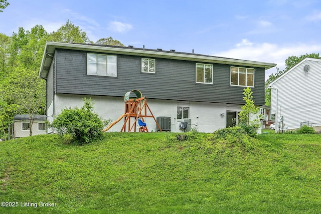 rear view of house with brick siding, cooling unit, and a yard