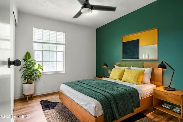 bedroom featuring wood finished floors, baseboards, and a ceiling fan