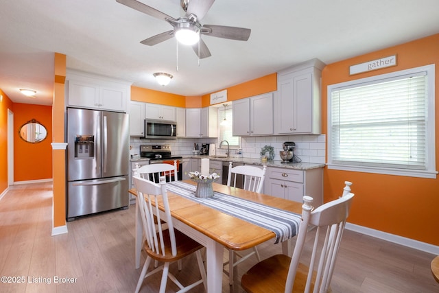 7411 Colt Dr, Louisville, KY 40214 - kitchen featuring backsplash, a sink, baseboards, light wood-style floors, and stainless steel appliances