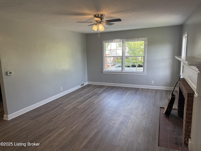 unfurnished living room featuring a fireplace, a ceiling fan, dark wood-style floors, and a textured ceiling